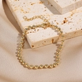 Dettaglio del bracciale a sfere dorate con finitura lucida su sfondo in pietra naturale - Stile Catena a Sfere Dorata