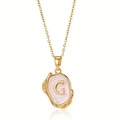 Detailopname van de vintage gouden letter G hanger met roze emaille aan een ketting - Goud G