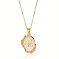 Detail van gouden vintage ketting met letter M hanger op parelmoer emaille achtergrond - Goud M