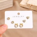 Close-up of three pairs of 16K gold plated stud earrings with zircons on display card - Round Heart And Bowknot Style (0026-1)