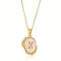 Macro detail van de gouden letter X munt hanger ketting met parelmoer inleg textuur - Goud X