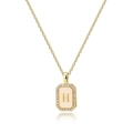 Macro detail of golden rectangular pendant with letter H and white zircon stones - Letter H