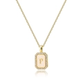 Macro detail of gold letter P pendant with sparkling zircon and white enamel shell - Letter P