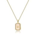 Close-up of golden rectangular pendant with letter R, shell base and zircon crystals - Letter R