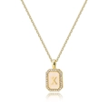 Detailed close-up of golden square pendant with zircon letter X and shell finish - Letter X