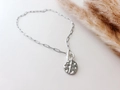 Detail van zilveren paperclip ketting met knevelsluiting en kruis hanger voor dames - Kruis Munt Hanger / Zilver
