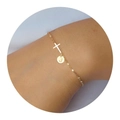 Close-up of golden cross bracelet with round letter J charm on female wrist - Letter J