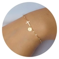 Close-up of golden cross bracelet with a round pendant engraved with the letter L - Letter G