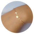 Detail of gold chain bracelet with a cross pendant and letter N circular tag on wrist - Letter N