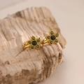 Macro detail of 18K gold plated flower earrings with green zircon stones on stone - Green