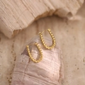 Dettaglio di orecchini a cerchio a U intrecciati in oro su sfondo in pietra naturale - Design Corda Torcigliata a Forma di U (EH328)
