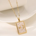 Macro detail of rectangle tarot pendant with gold sun moon motif on white enamel - White