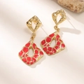 Détail de boucles d'oreilles dorées géométriques avec émail rouge et formes évidées - Rouge