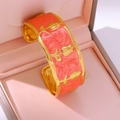 Detailed macro view of pink marble enamel and gold rose reliefs on a vintage cuff bracelet - Orange