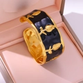 Macro shot of gold rose relief on black enamel vintage cuff bangle with wave texture - Black