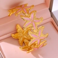 Vista macro di stelle marine in smalto rosa su un bracciale a C placcato in oro - 18K / Rosa