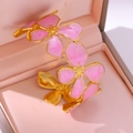 Gouden open armband met roze emaille bloemhangers en een elegante afwerking - Roze