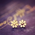 Elegante vergoldete Sonnenblumen-Ohrstecker für Damen auf strukturiertem lila Hintergrund - Gänseblümchen / Gold