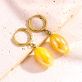 Détail de boucles d'oreilles créoles dorées avec pendentifs ovales en résine aurore - Jaune Luxe & Or