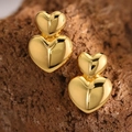 Macro shot of 3D layered heart stud earrings with shiny gold finish on a natural rock - 3D Double Heart (EH100)