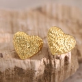 Macro shot of gold heart studs with textured hammered finish on a natural stone base - Hammered Texture (EH084)