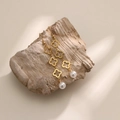 Elegant gold hollow four-leaf clover drop earrings with white pearl on a rustic stone base - Gold Hollow Clover Style (EH182-2)