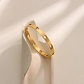 Gold plated titanium steel bangle with hollow heart patterns on white stone background - Equidistant Hollow Heart Style (SZ006)