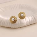 Dettaglio di orecchini ottagonali dorati con perla bianca centrale su un piatto in ceramica - Stile Perla Ottagonale (EH211)