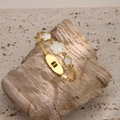 Detail of gold titanium steel bangle with shell flower charms and zircon stones - White Mother of Pearl Flower Style (SZ003)