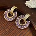 Detailed macro view of C-shaped gold earrings with purple marquise gems and pavé zircons - Gold-Purple