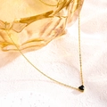 Detail of heart pendant necklace in gold finish with a black birthstone on a textured background - September Black