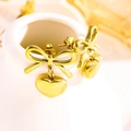 Dettaglio di orecchini a fiocco e cuore dorati appesi a un vaso di ceramica bianca - 5603 Orecchini Bottone Cuore Fiocco Tutto Oro