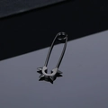 Macro shot of matte black punk safety pin earrings with sharp metal cone rivets - Black