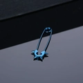 Detail view of blue punk safety pin earrings with four cone spikes on a black surface - Blue