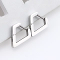 Macro shot of silver geometric stainless steel huggie earrings on a white textured stand - Irregular Heart Steel