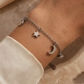 Elegante bracciale in acciaio al titanio con stella e mezzaluna su sfondo di manica in seta - Oro 18K / Argento