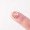Gros plan d'un piercing nez alien or rose sur le bout du doigt montrant la petite taille - 8mm / Or rose