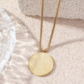 Gold box chain necklace with a round cream pendant shown on a natural textured stone background - Gold