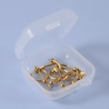 Makroansicht von 12 goldenen Piercing-Schmuckstücken aus Edelstahl in einer Plastikbox - Gold