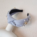 Elegant light blue knotted headband with faux pearls and gold beads on a white mannequin - Grey Green