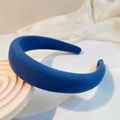 Close-up of Navy blue padded headband with diagonal twill fabric texture on white stand - Blue