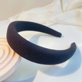 Detail view of a thick black padded headband with textured fabric on a white display - Black