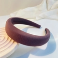 Close-up of a padded knit headband in dark plum purple on a spiral display stand - Coffee