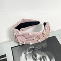Diadema de tela rosa con perlas y lazos decorativos sobre una revista de moda - Rosa