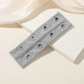 Detalle de diadema de punto gris con ocho ojales metálicos estilo punk en soporte blanco - Gris