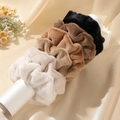 Plush faux fur scrunchies in earth tones displayed on a cylinder stand with soft lighting - Multicolor Combo