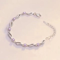 Detailed macro view of wave-shaped silver bracelet with purple round zircon and lobster clasp - Purple