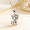 Silver cat pendant necklace with heart-shaped clear crystals on a cream silk background - Necklace / White
