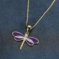 Detailed macro view of a gold dragonfly pendant necklace with purple wings and zircons - Purple