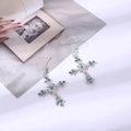 Elegante zilveren kruis oorbellen met blauwe strassteentjes op vintage magazine - Oorbellen / Blauw